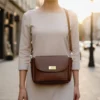 Compact caramel brown genuine leather flap bag with grain texture and long adjustable shoulder strap